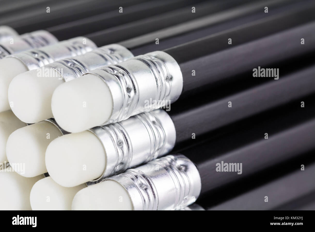 Close up of new black pencils with white erasers stacked on an angle