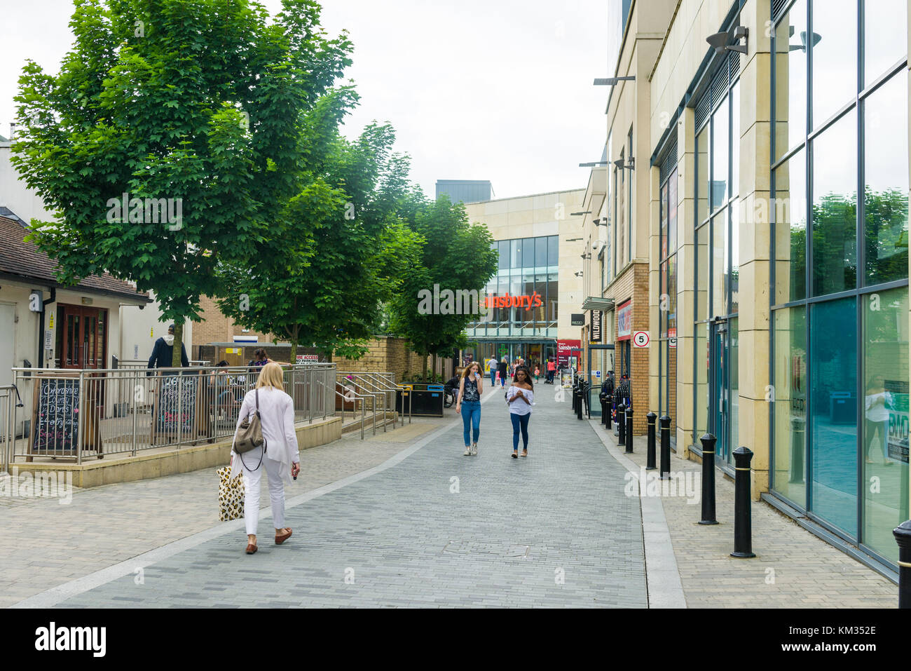 Shoppers walking around Pioneer Square urban regeneration with Sainsburys supermarket in background, Bicester town, England, United Kingdom Stock Photo