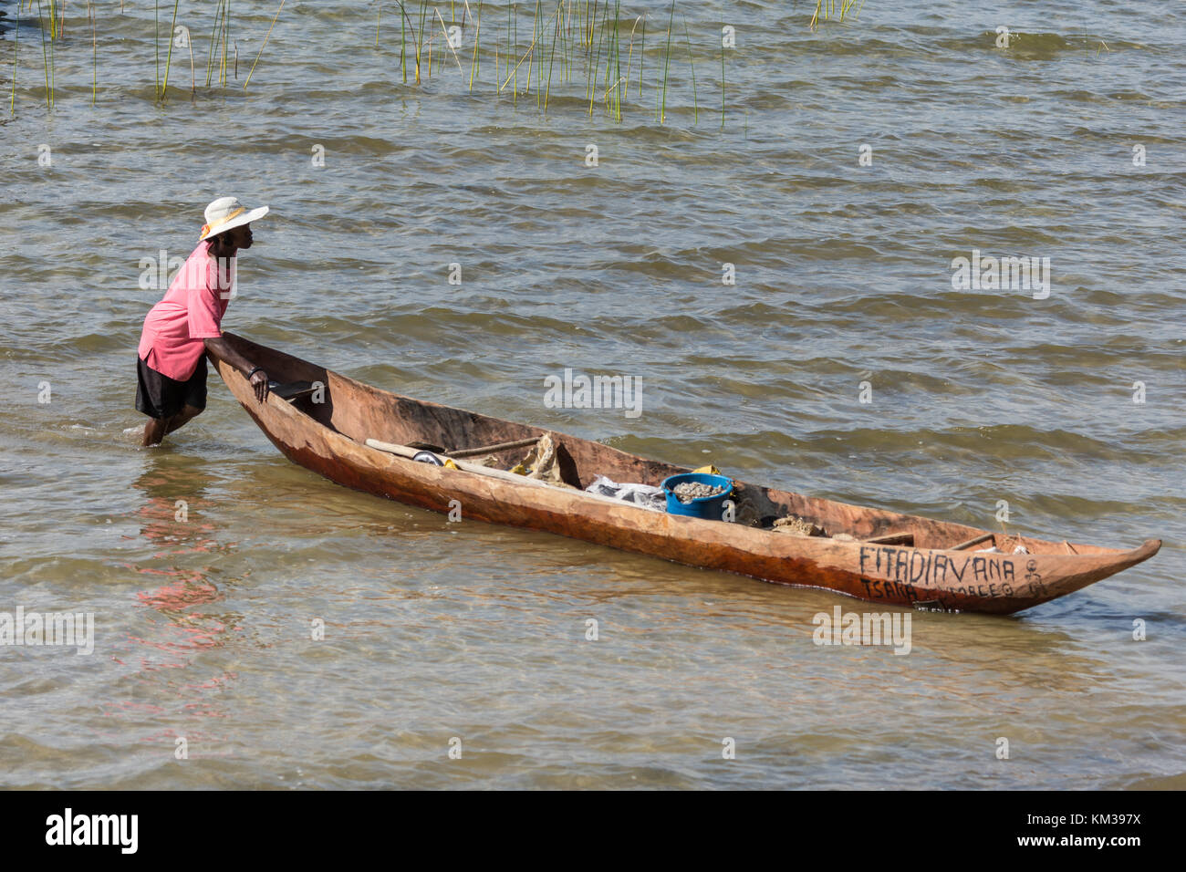 A Malagasy woman push a dugout canoe in Lake Ampitabe. Madagascar, Africa. Stock Photo