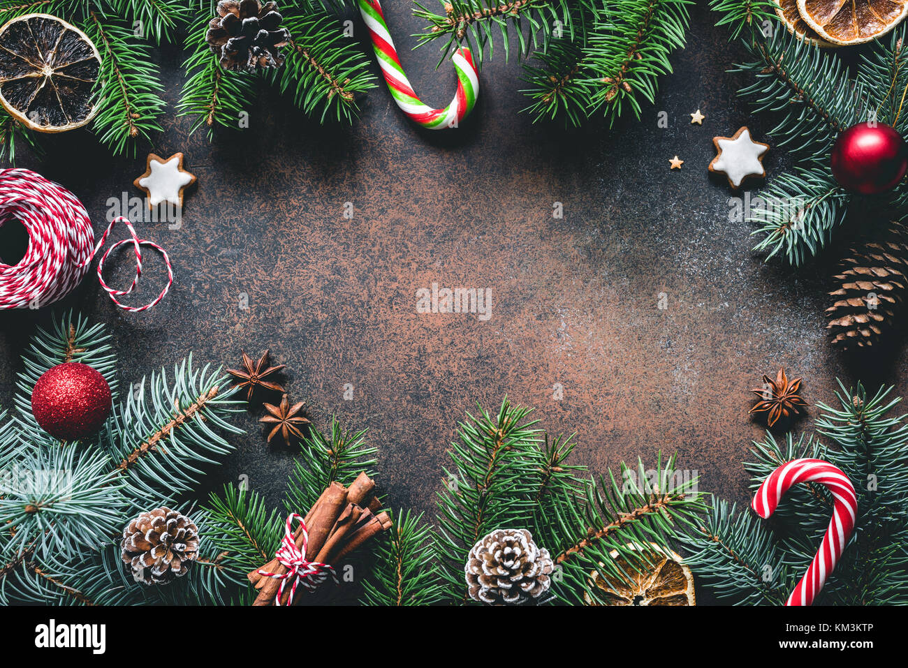 Christmas frame with fir tree branches, candy canes, gingerbread cookies, spices and dried oranges. Copy space for text Stock Photo