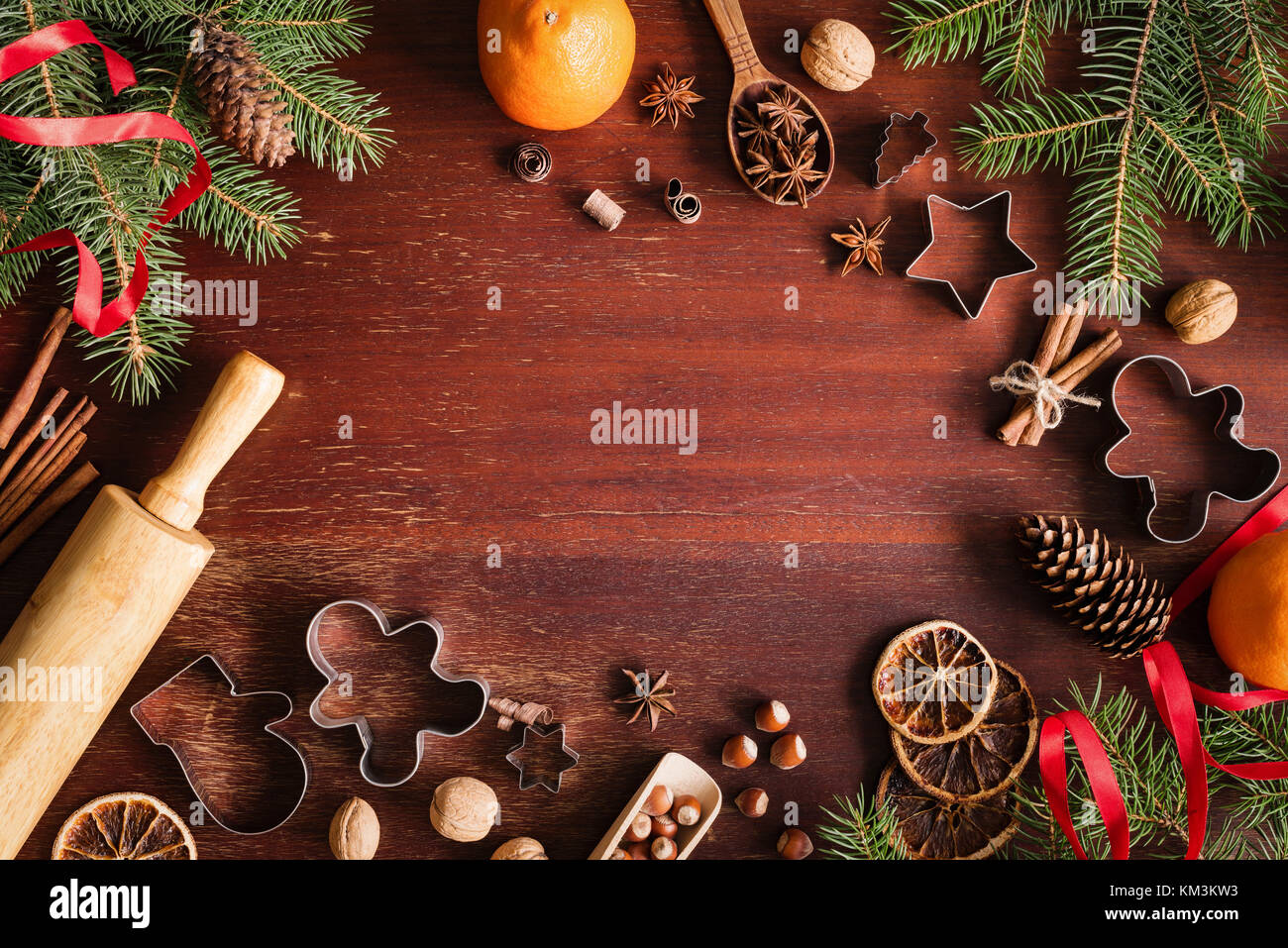 Christmas or New Year frame border with gingerbread cookies, nuts, spices, fir tree branches and cookie cutters on wooden table. Top view with copy sp Stock Photo