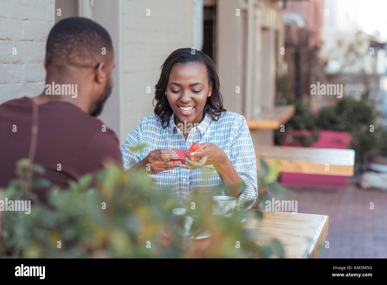 Smiling young African woman opening a present from her boyfriend Stock Photo