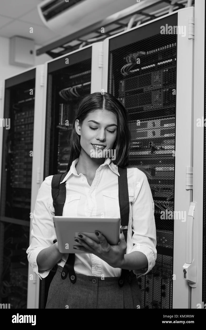 Technician using tablet pc while analysing server in large data center Stock Photo