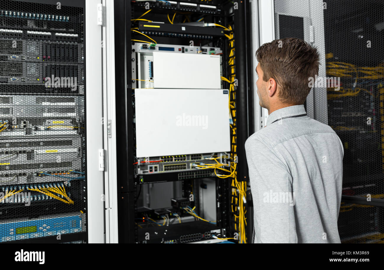Young man is standing next to the racks with computer equipment Stock ...