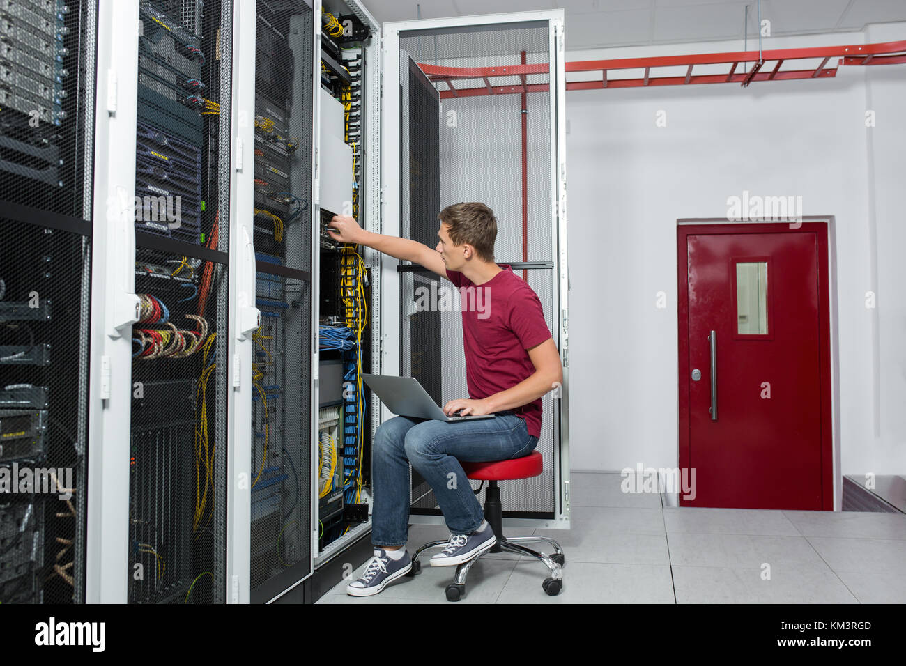 Young man is standing next to the racks with computer equipment Stock ...