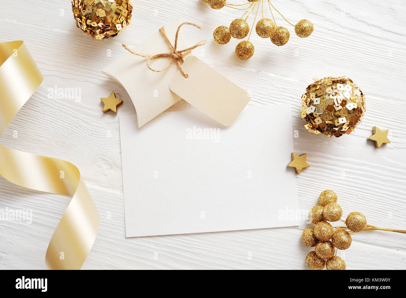 Mockup Christmas greeting card top view and gold ball, flatlay on a white wooden background with a ribbon, with place for your text Stock Photo