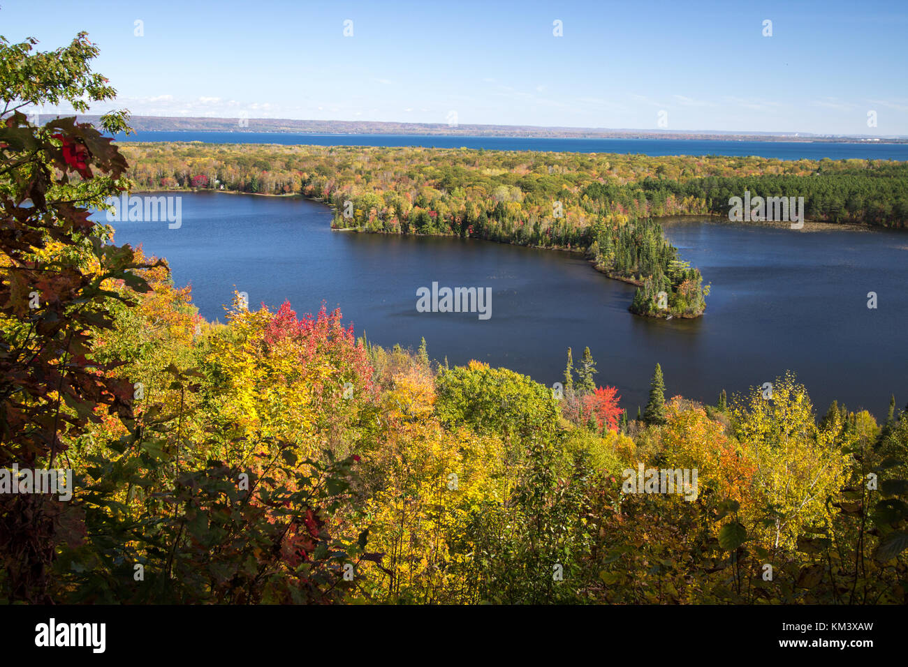 Vibrant autumn color in the northern Michigan forest with the vast blue waters of Lake Superior in the background at the Mission Hill Overlook Brimley Stock Photo