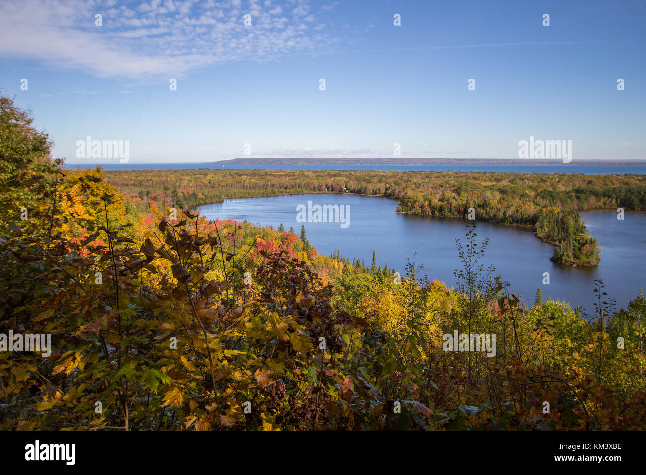 Vibrant autumn color in the northern Michigan forest with the vast blue waters of Lake Superior in the background at the Mission Hill Overlook Brimley Stock Photo