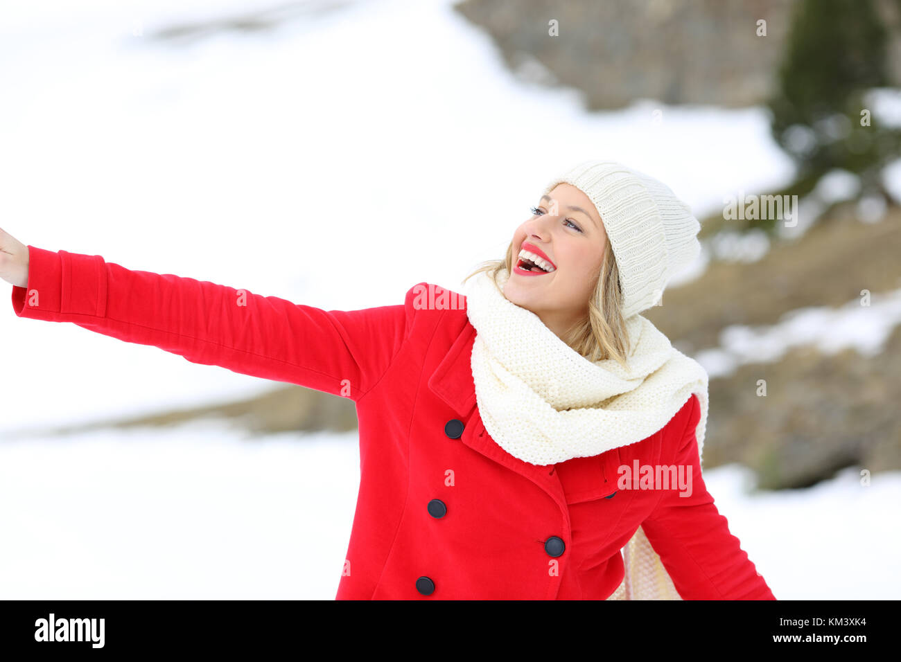 Portrait of a candid woman in red enjoying outdoors in a snowy mountain in winter Stock Photo