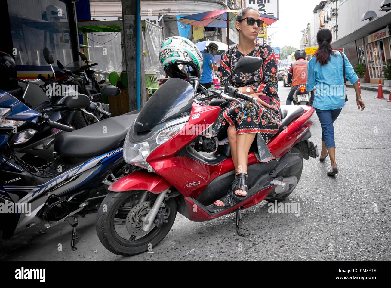 Woman sat on a scooter motorcycle waiting. Stock Photo