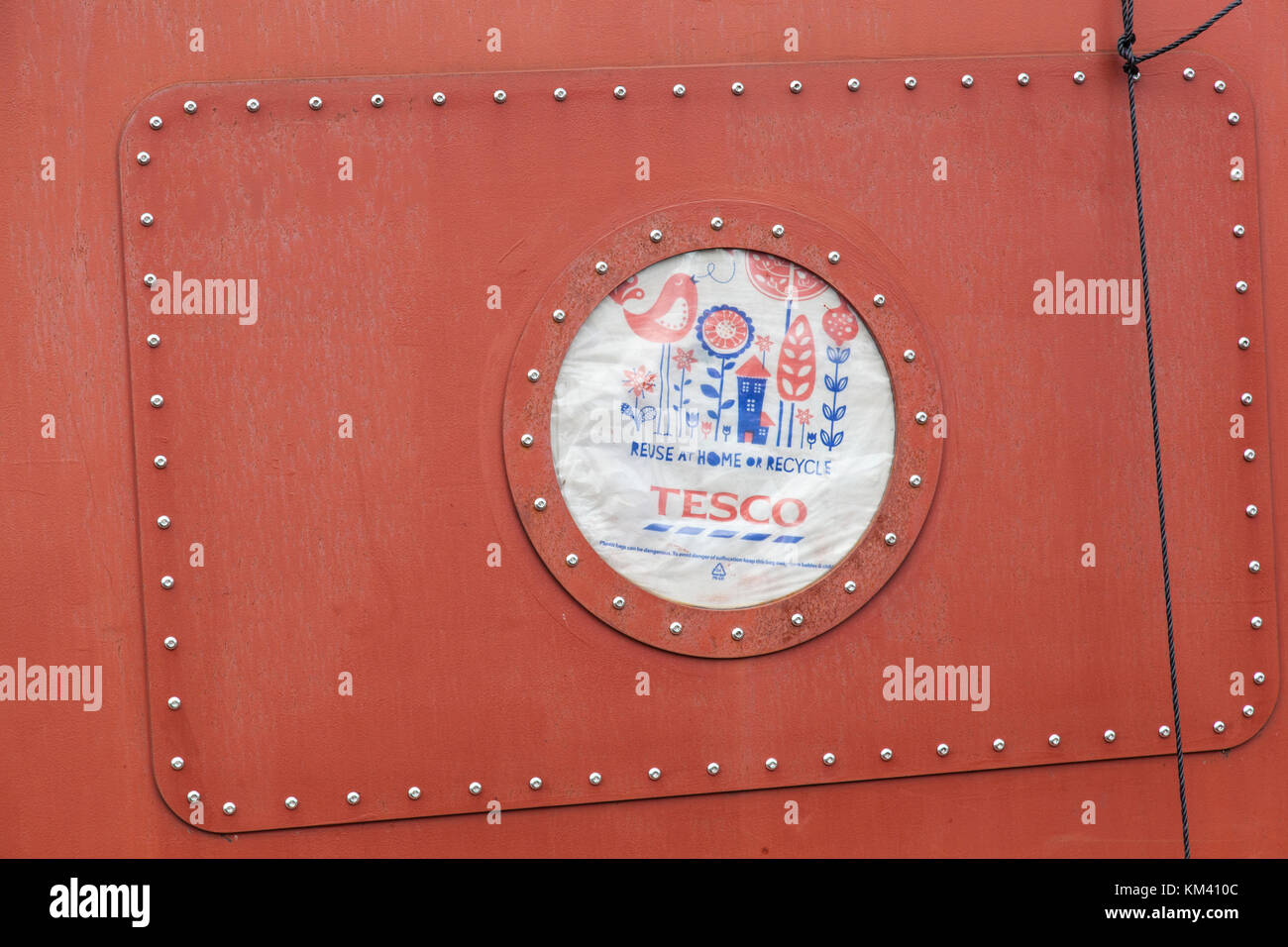 Close-up of a port-hole in a narrowboat covered with a plastic Tesco bag. Stock Photo