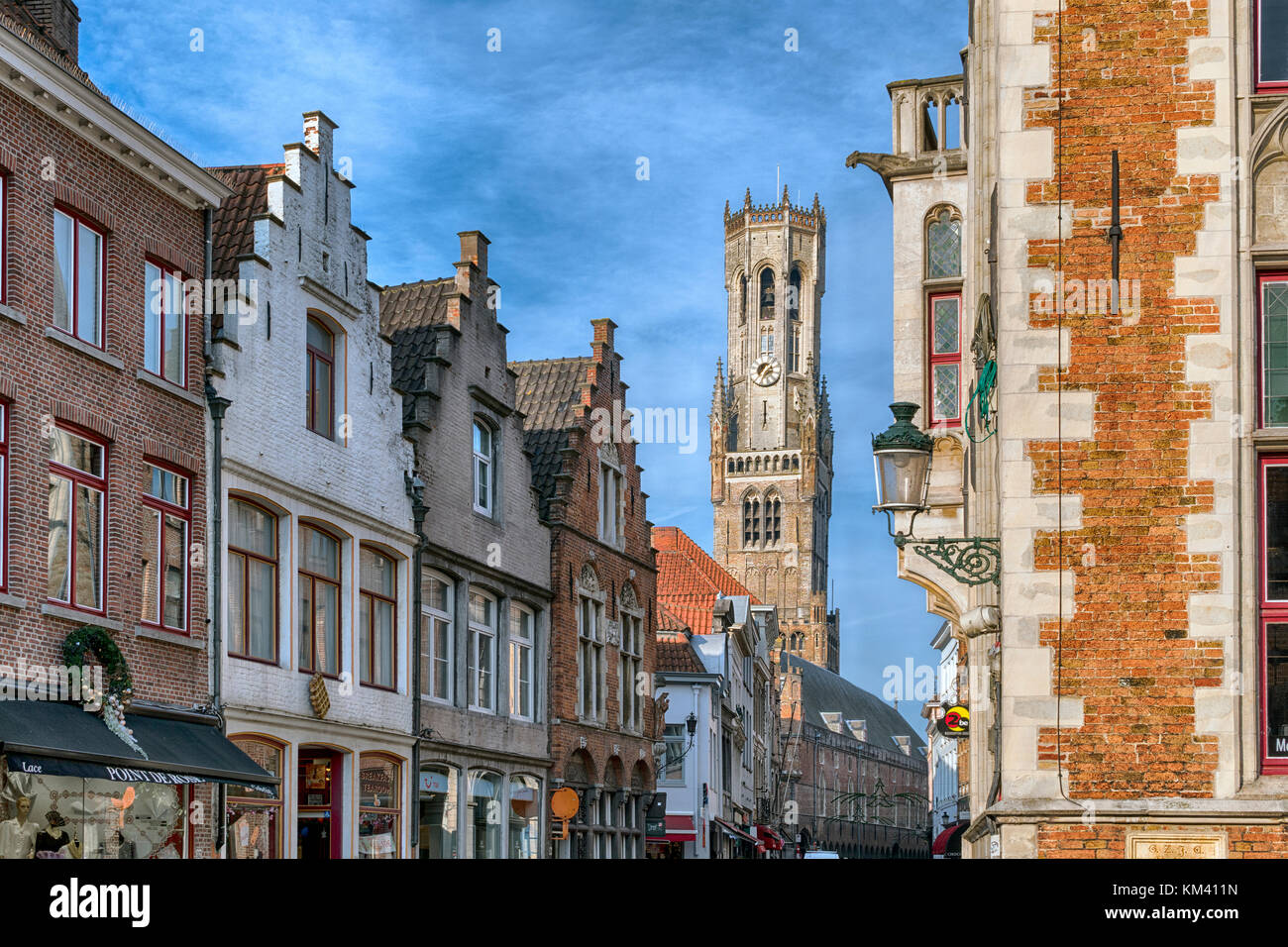 Typical Bruges architecture and shop fronts featuring chocolate and lace shops, the 83-metre high Belfry in the Markt (market square) Stock Photo