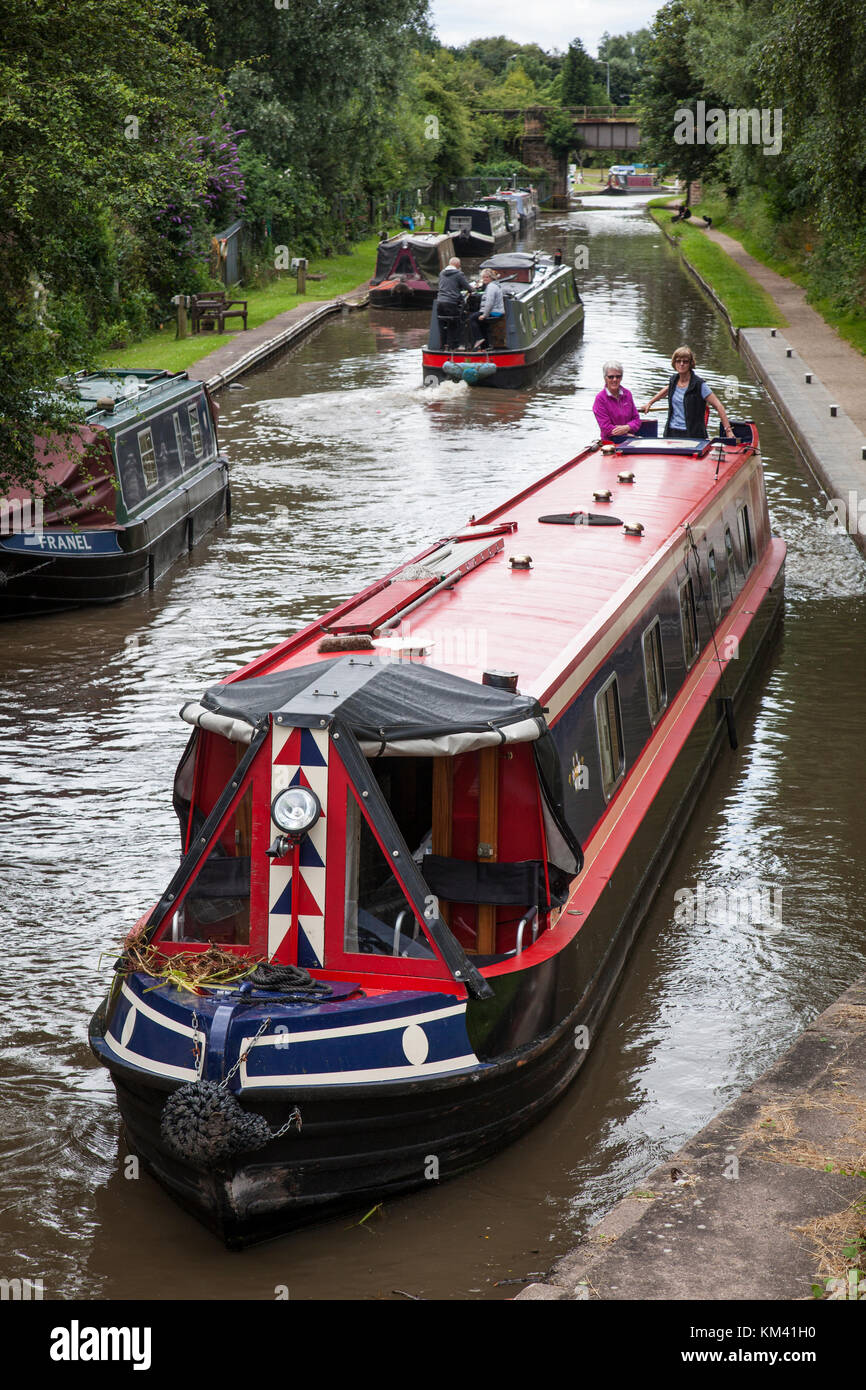 Narrowboats sail up and down past moored vessels on the Coventry canal near Tamworth, Staffordshire, England. Stock Photo