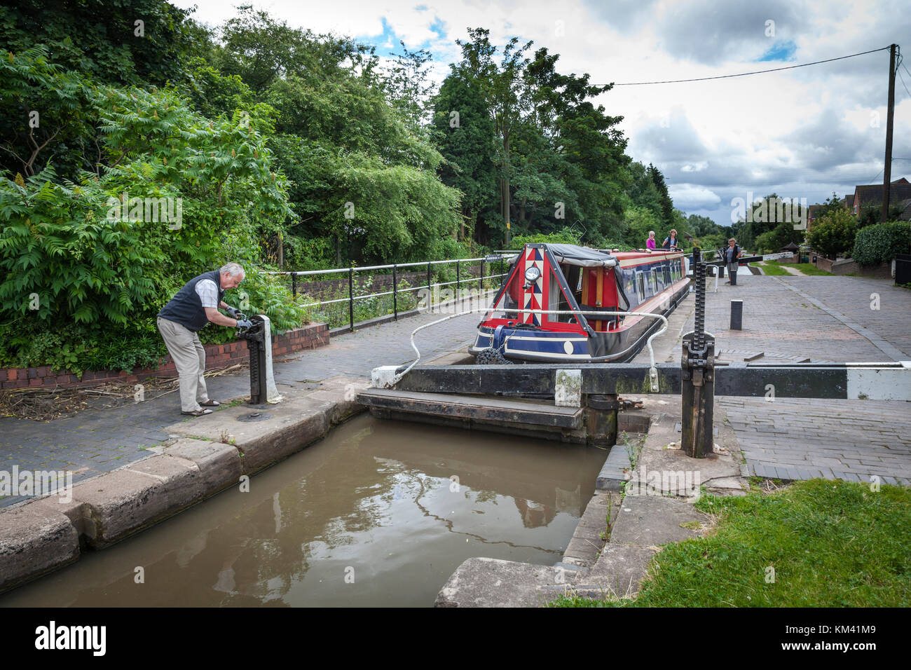 A man prepares to open a lock and release a narrowboat on the Coventry canal, Staffordshire, England. Stock Photo