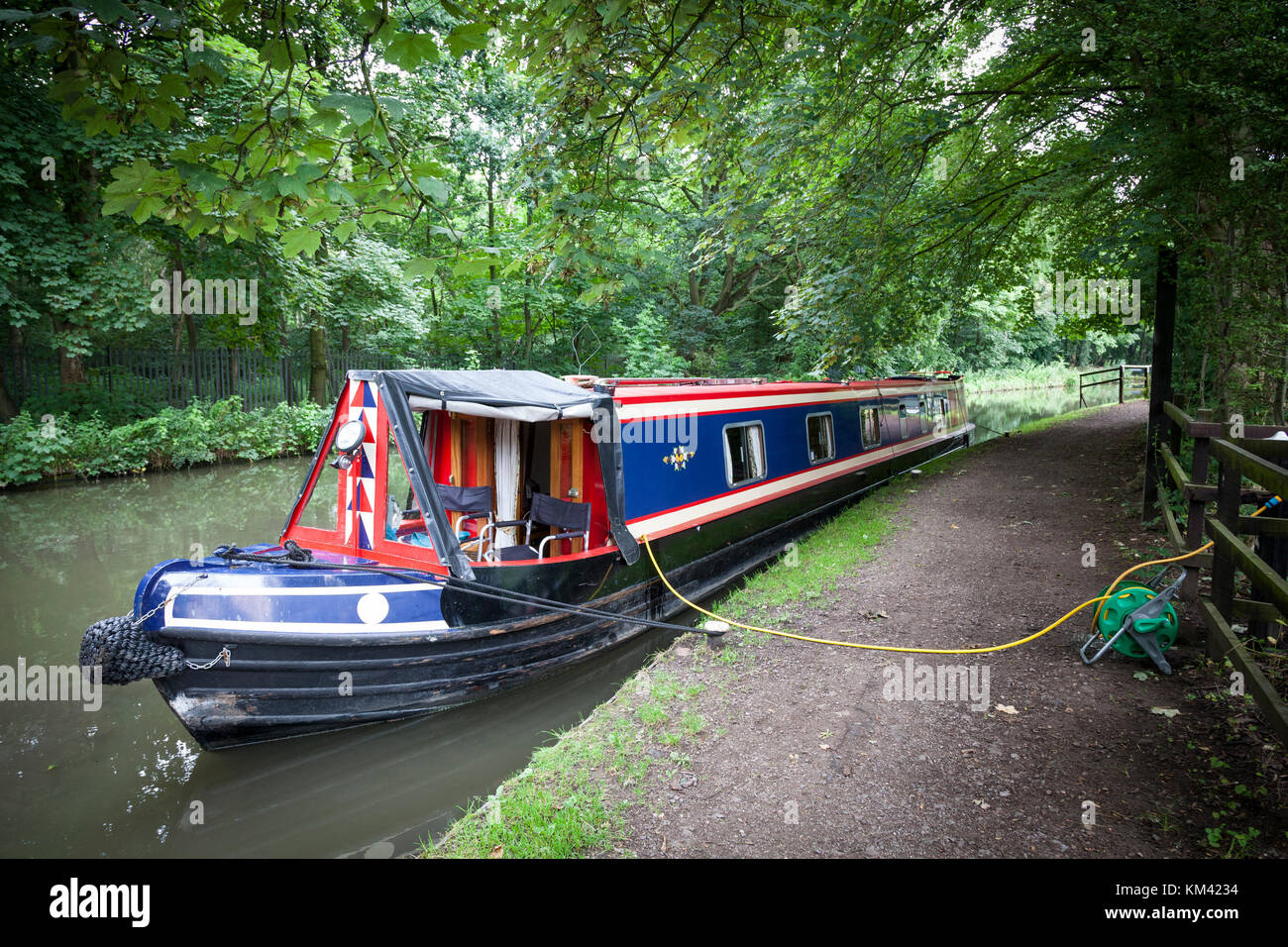 Narrowboat moored and having its water tanks filled with a hose on the ...