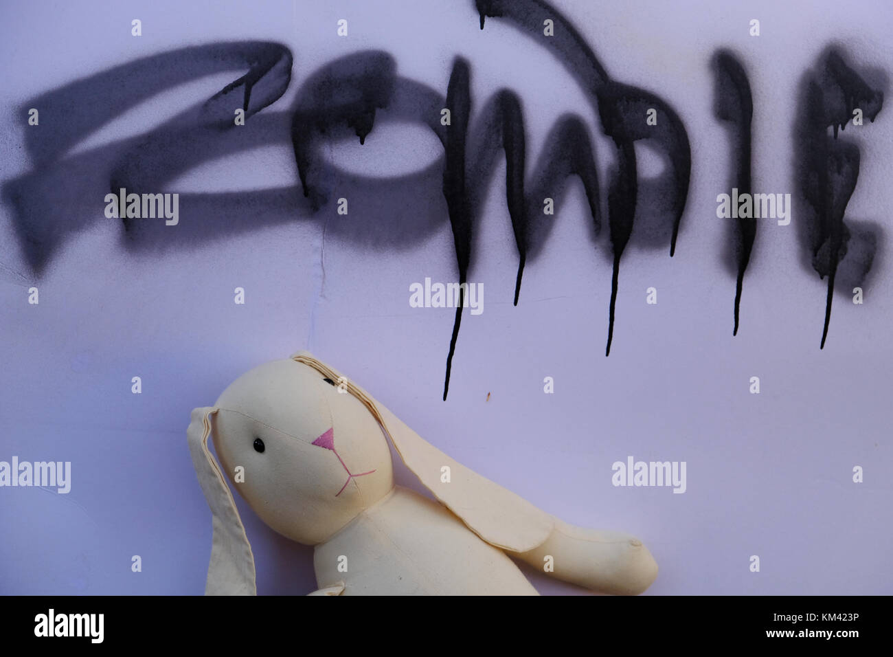 Toy rabbit under a zombie warning poster. Stock Photo