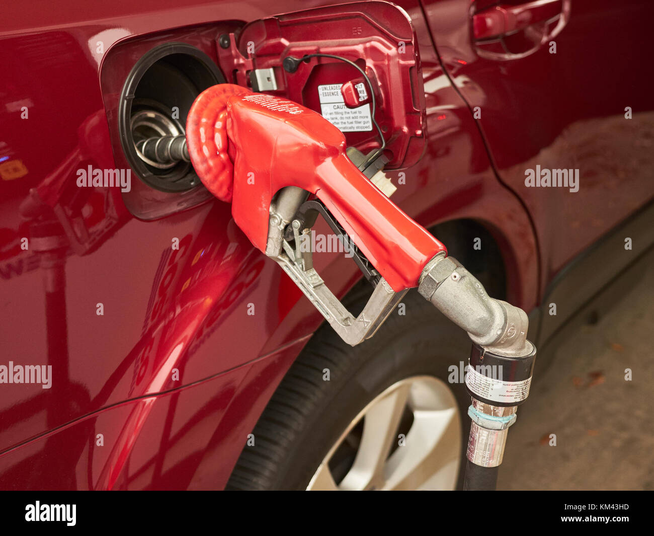 Gas pump handle in car filler, pumping gasoline into automobile for holiday travel. Stock Photo