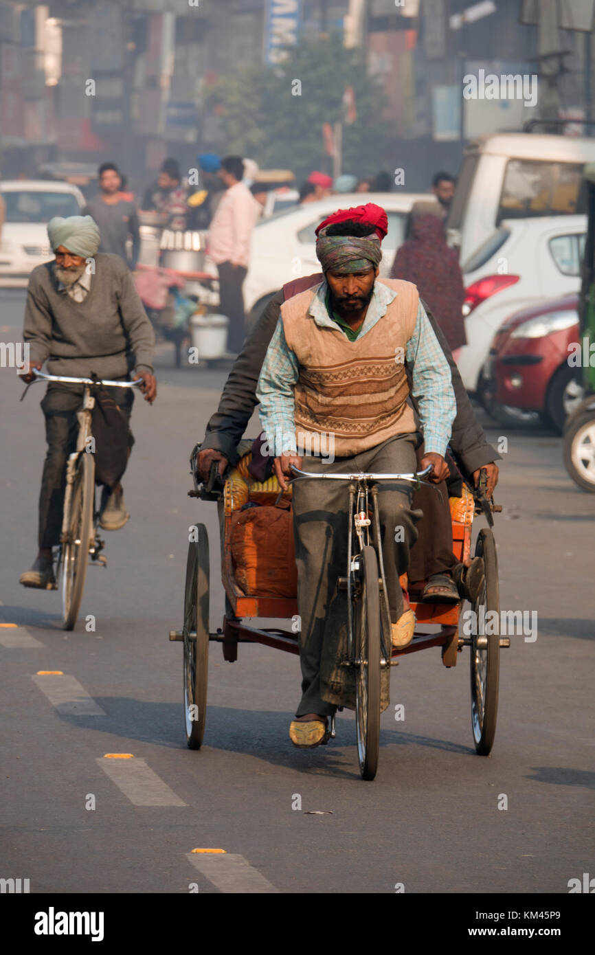 Punjabi Sikh man with turban and beard pedals cycle rickshaw with passenger, in Amritsar, India Stock Photo