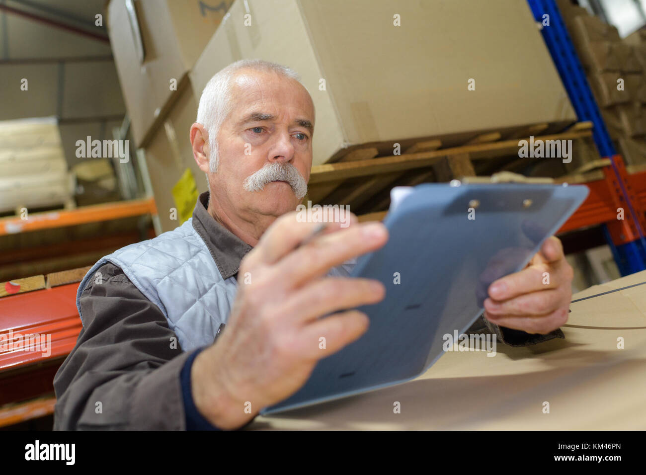 senior worker holding clipboard in warehouse Stock Photo
