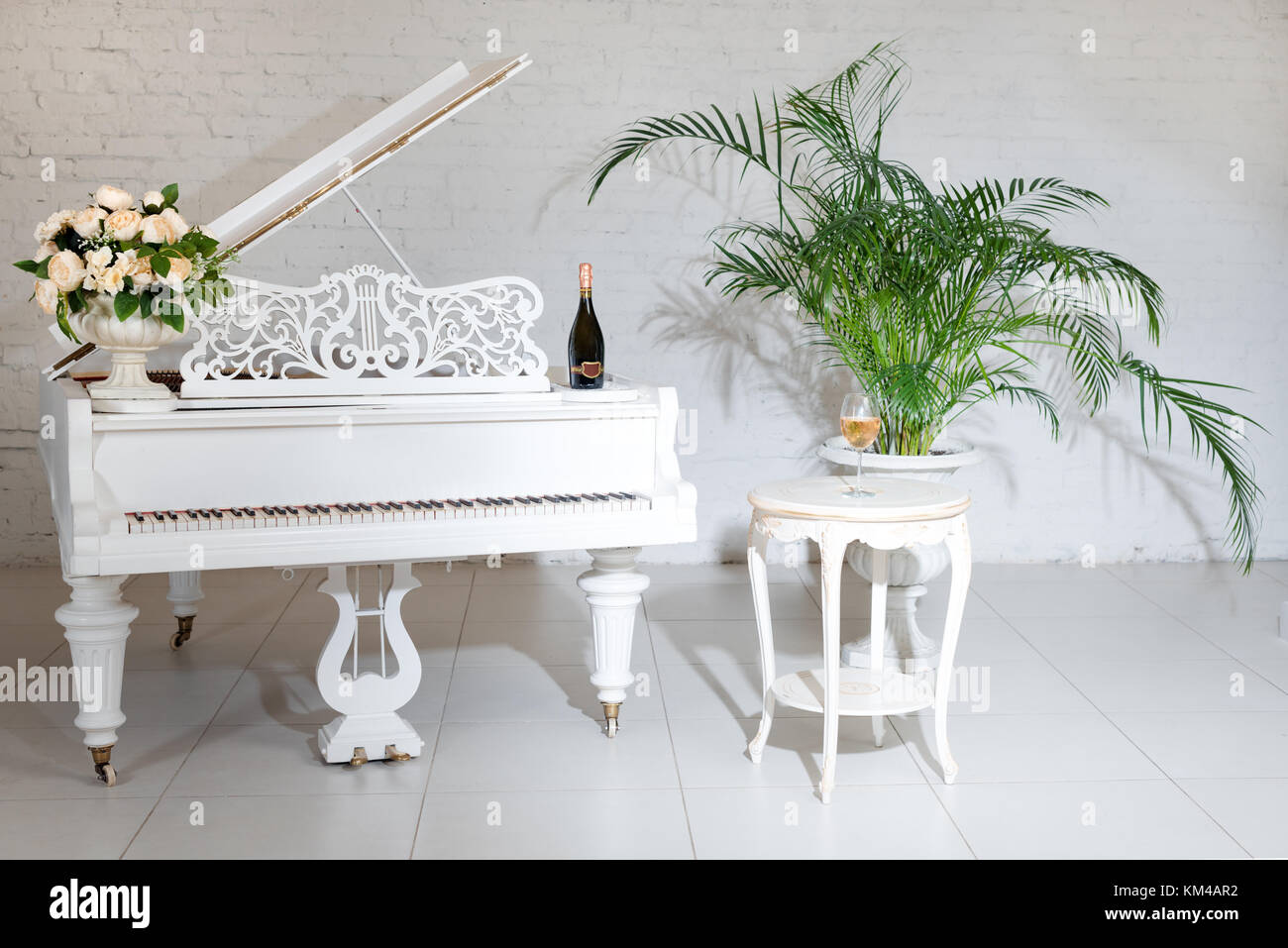 Grand piano in a luxury white classic interior with wine, palms and ...