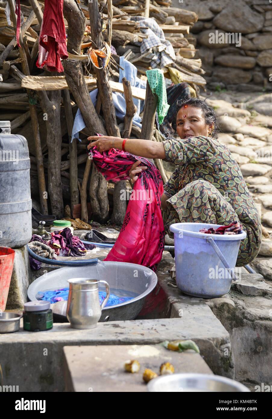 A woman washes laundry on a typical washing place on a street near