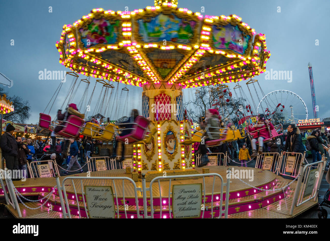 A chair-o-planes ride for young children at a fairground at sunset ...