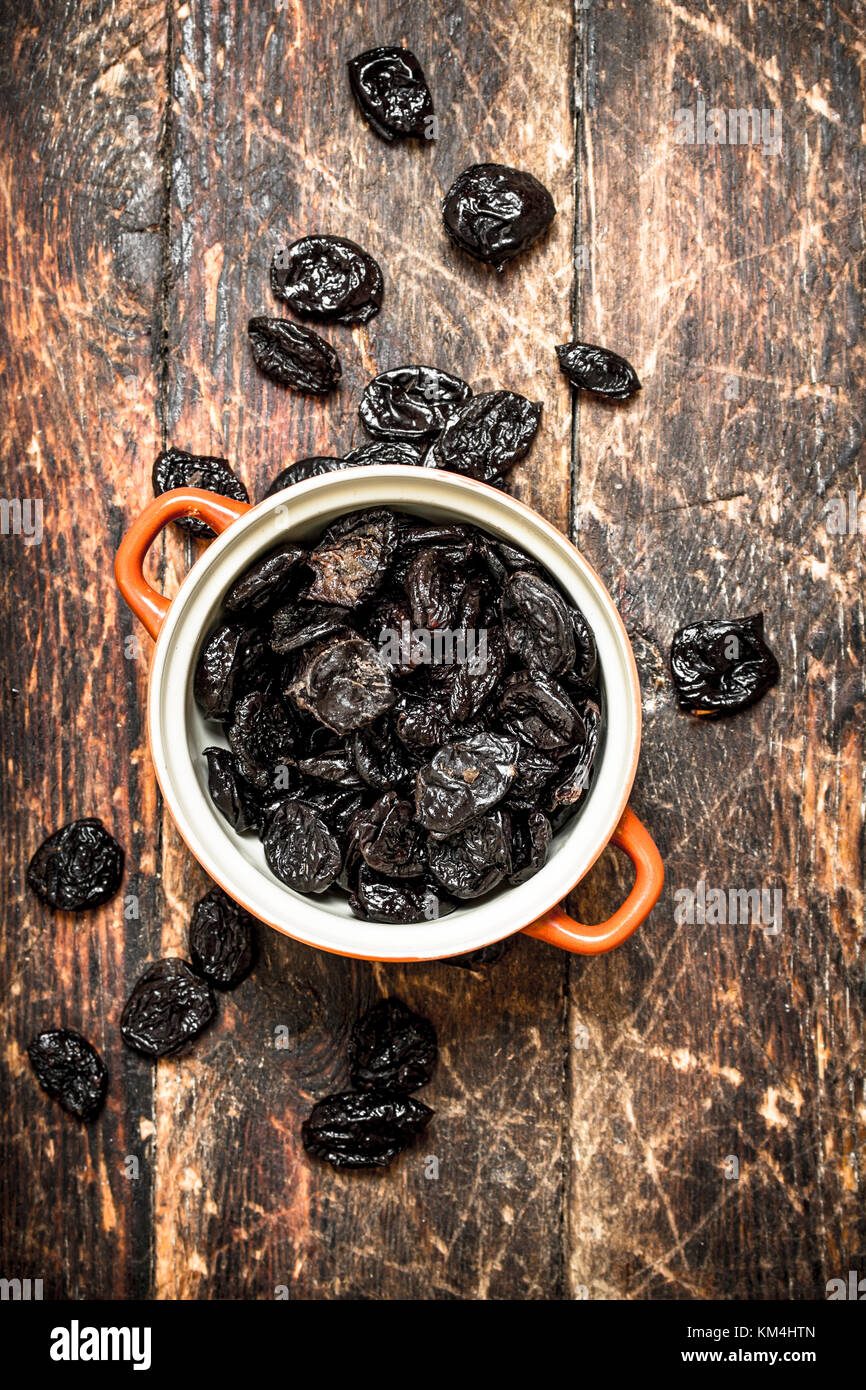 Prunes in a bowl. On wooden background. Stock Photo
