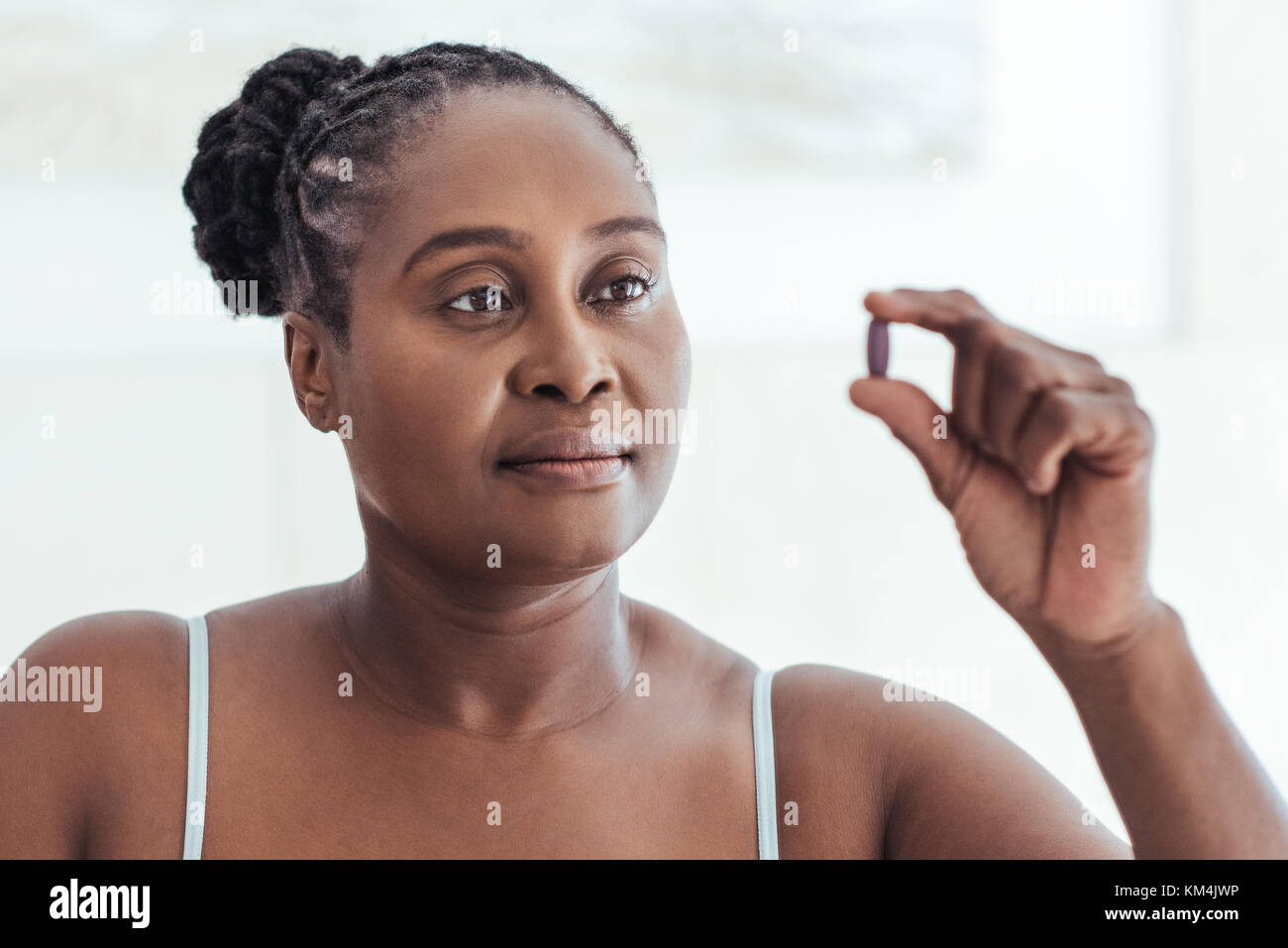 African woman looking at a pill in her hand Stock Photo