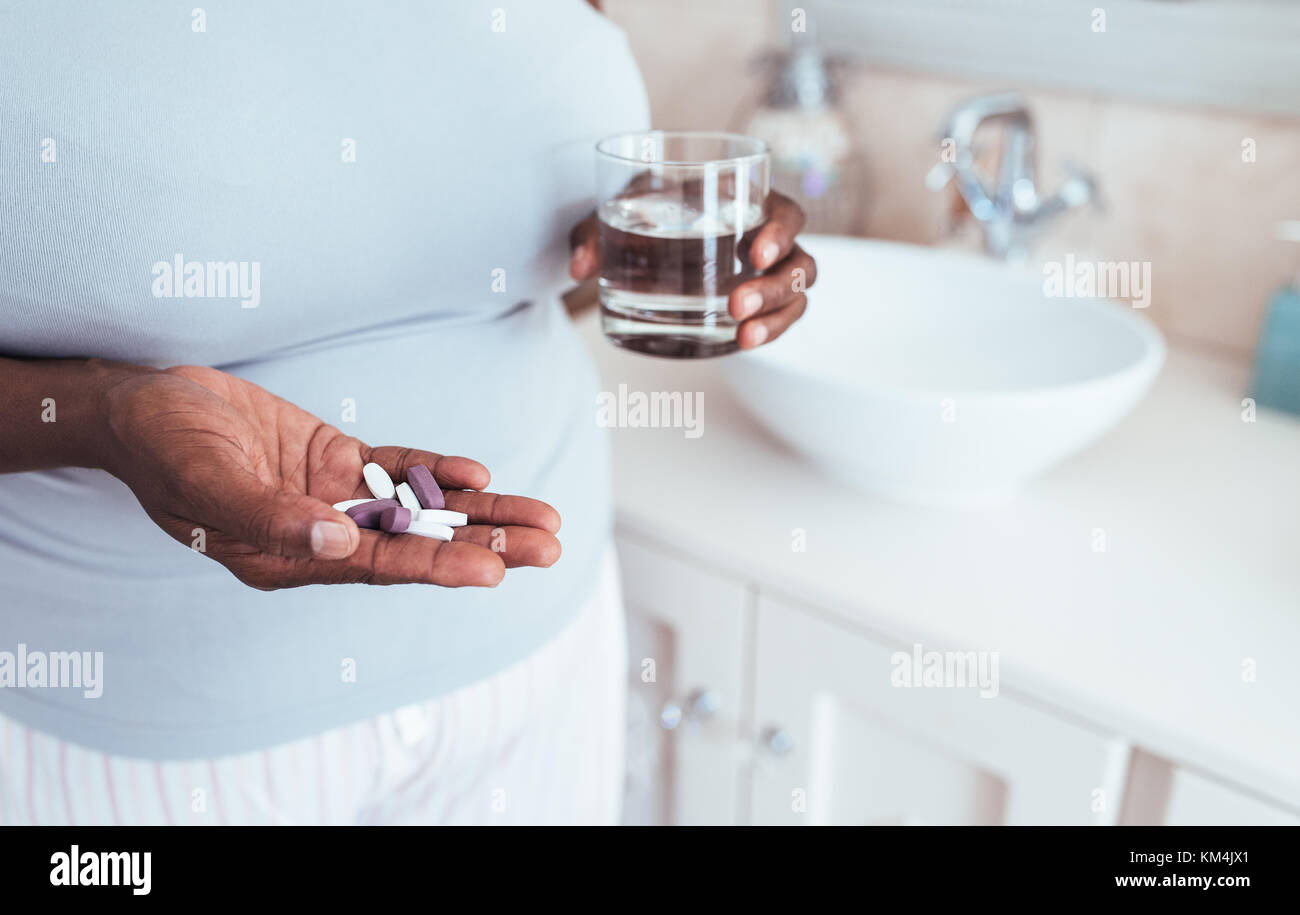 African woman holding pills and a glass of water Stock Photo