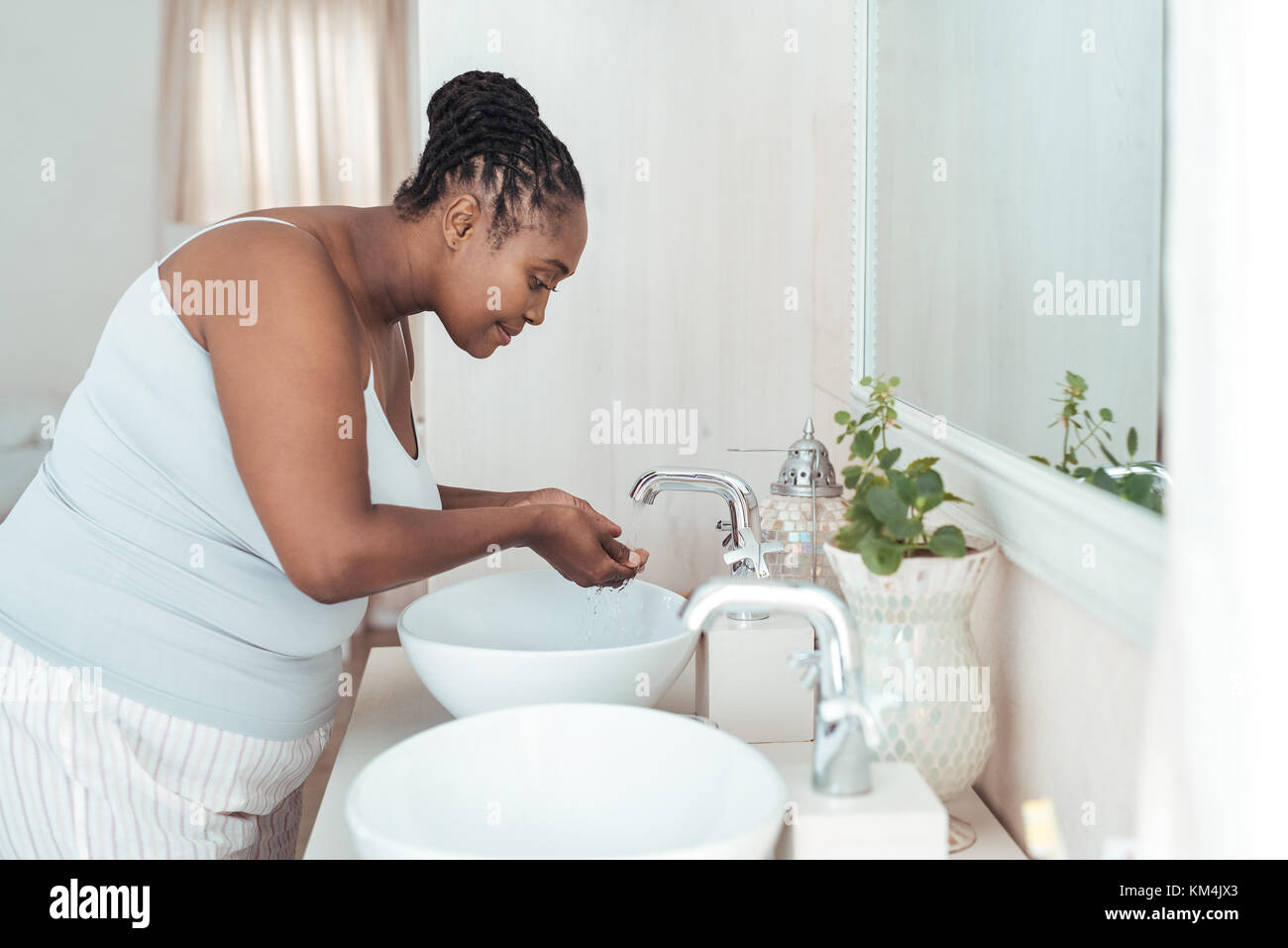 Young African woman washing her face in the morning Stock Photo