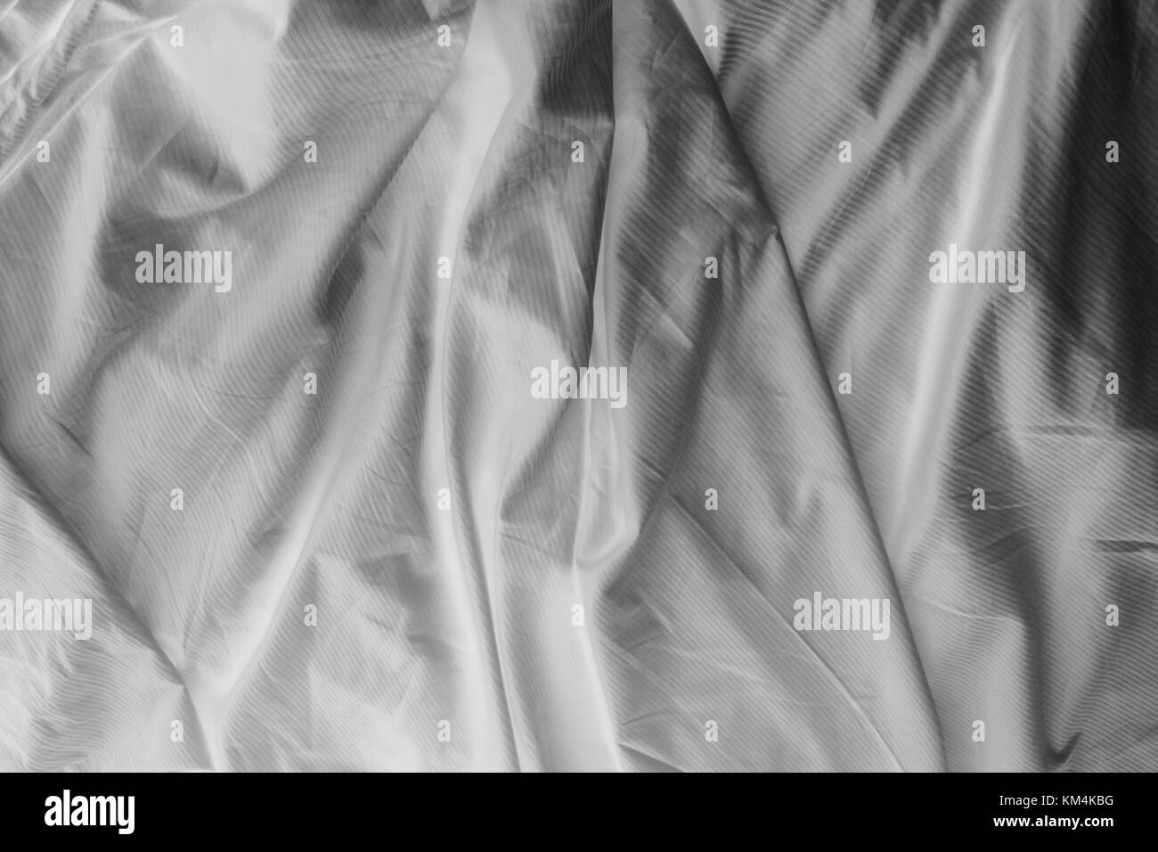 Black and white close up of wrinkled cotton sheets on bed. Stock Photo