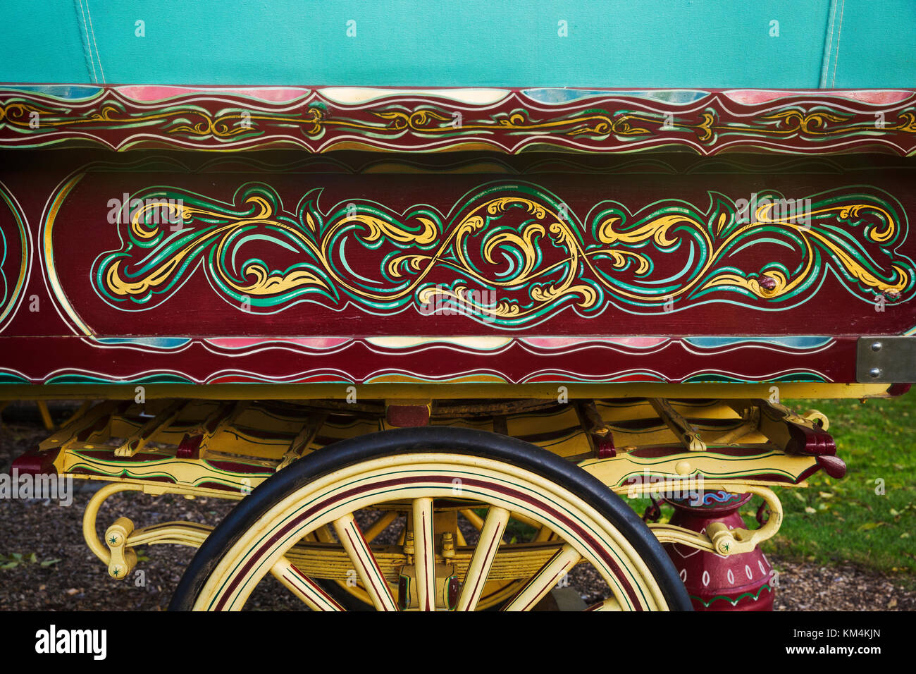 The painted decorated side panel of a bow top gypsy caravan and large wooden wheel. Stock Photo