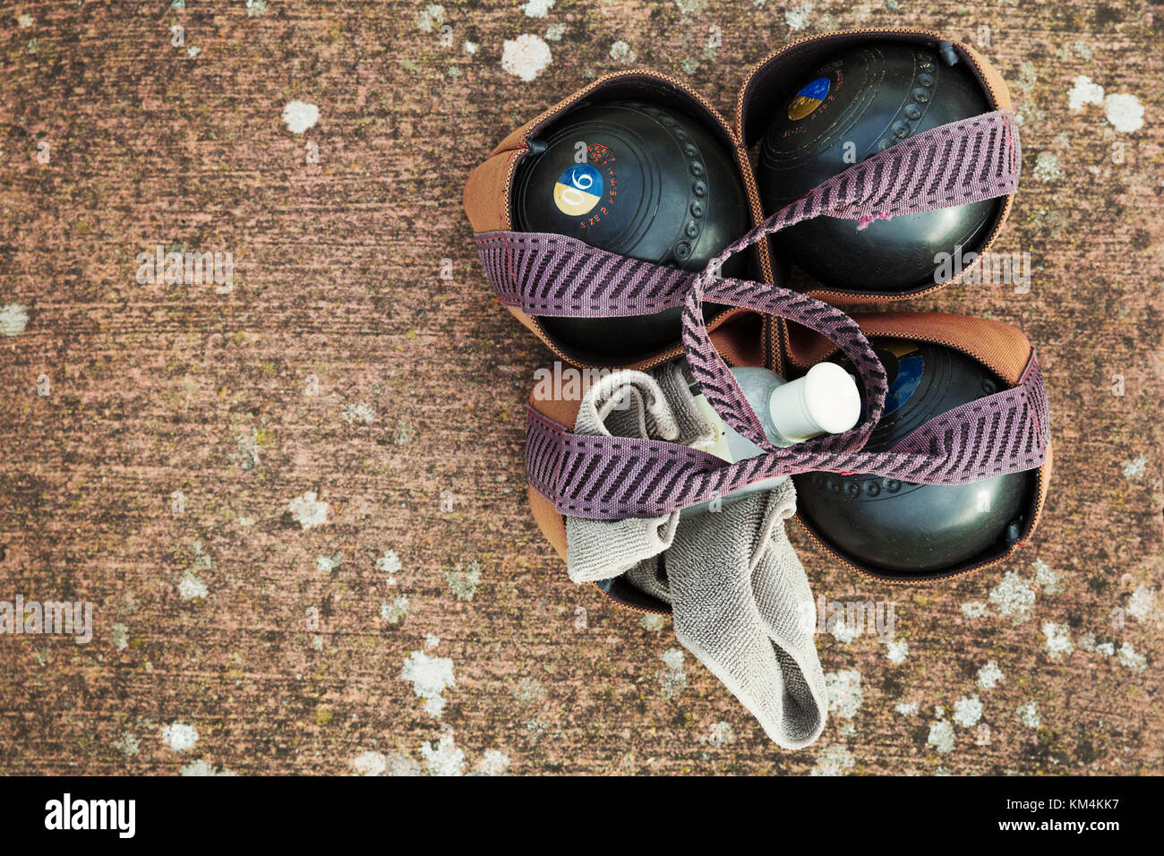 Overhead view of four wooden lawn bowls in a ball carrier with a cloth to clean them. Stock Photo