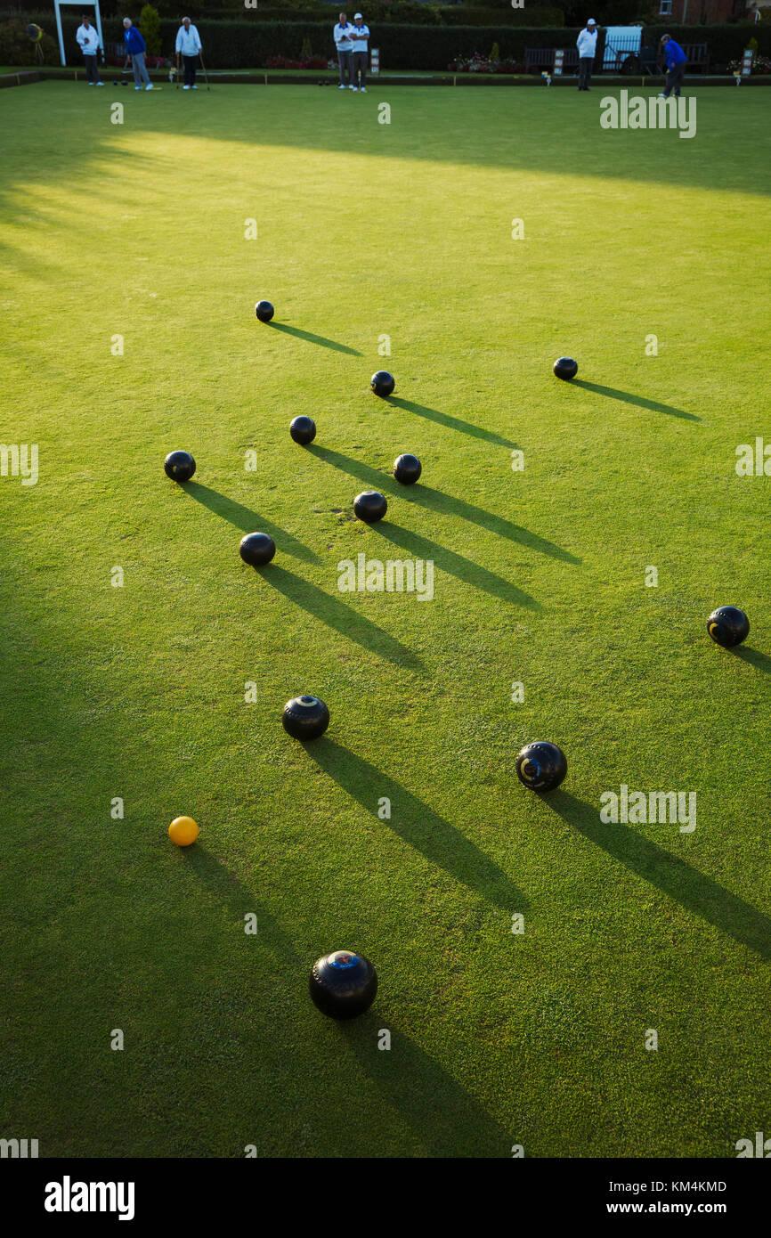 Lawn bowls balls positioned on a smooth playing surface, a bowls green