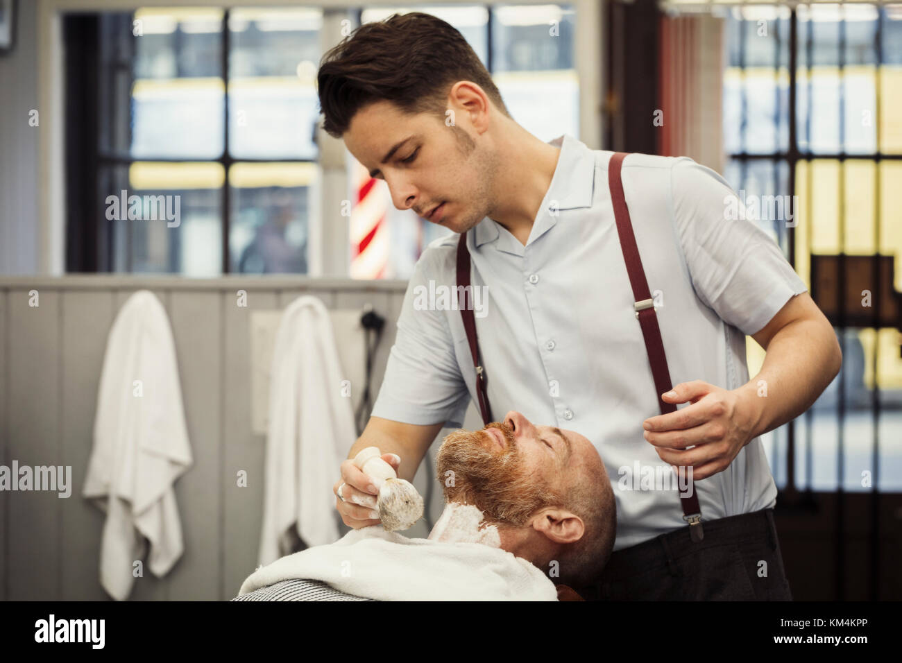 A customer sitting in the barber's chair, having a wet shave. A man