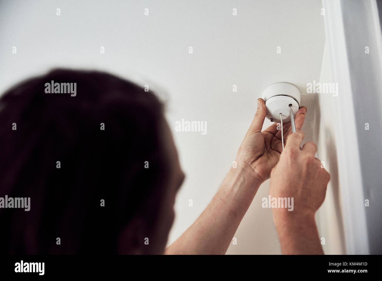 An electrician screwing the cap on a light fitting on the ceiling Stock ...