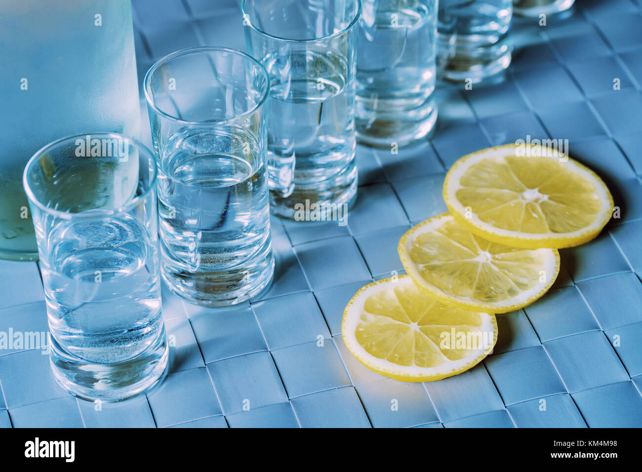 Vodka shot glass and lemon on blue surface Stock Photo Alamy