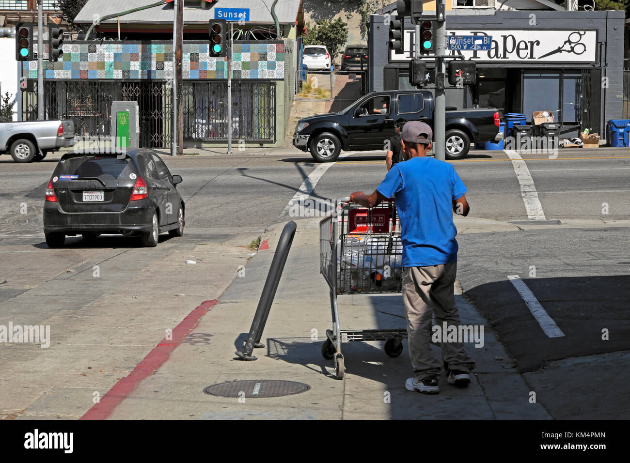 Man pushing shopping cart filled of empty bottles and rubbish Sunset Blvd in Echo Park neighborhood of LA Los Angeles California US USA KATHY DEWITT Stock Photo