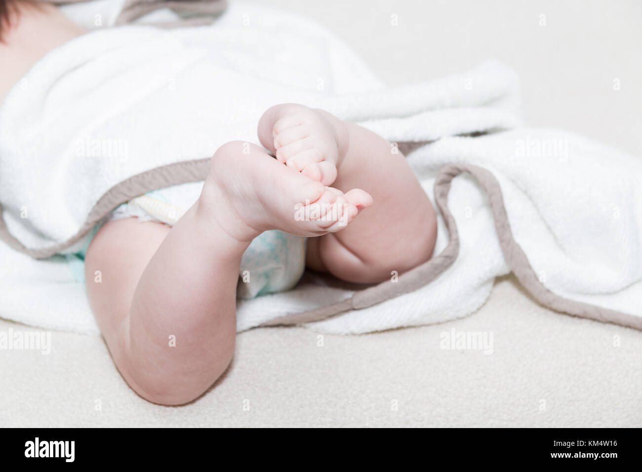 White towel around cute newborn feet. Close up picture of new born baby feet on a white sheet. Stock Photo