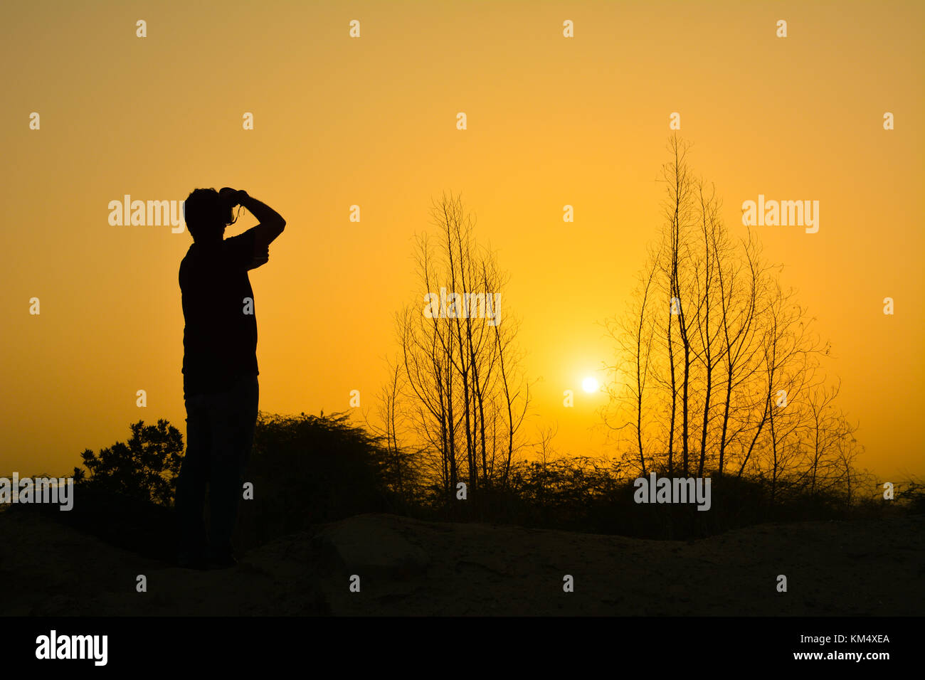 Sunrise in desert with beautiful yellow sky and silhouette photographer Stock Photo