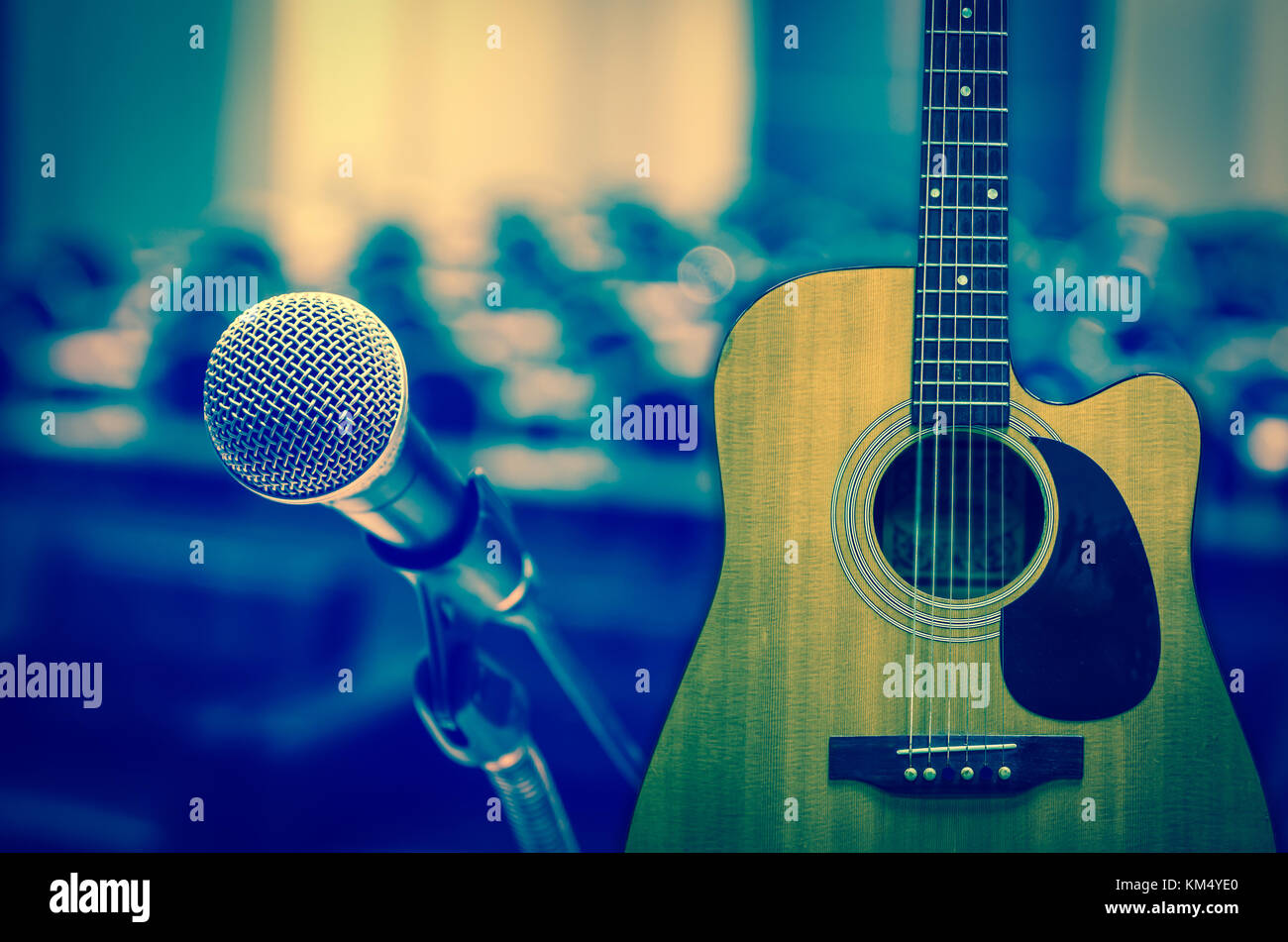 Guitar and Microphone over the Abstract blurred photo of concert or conference hall or seminar room background Stock Photo