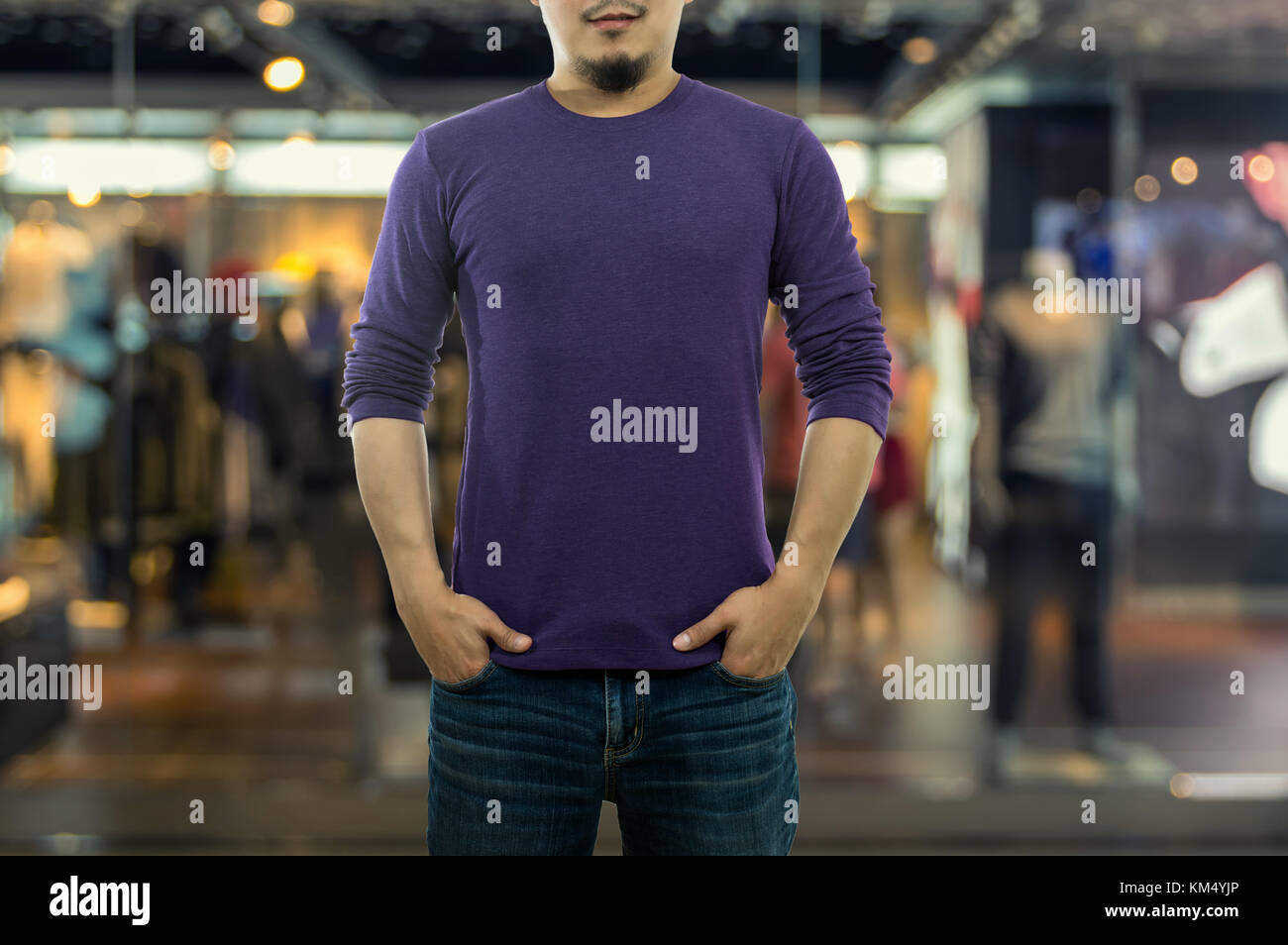 A guy wearing blank mock neck long t-shirt while standing over the Abstract blurred photo of clothing store in a shopping mall, shopping concept Stock Photo