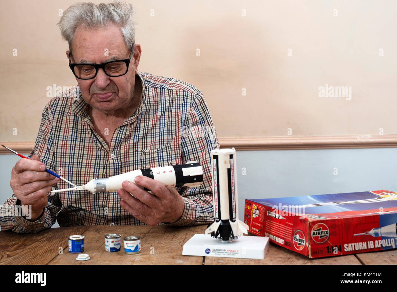 Elderly man making an Airfix plastic model Saturn Apollo 7 space rocket Stock Photo