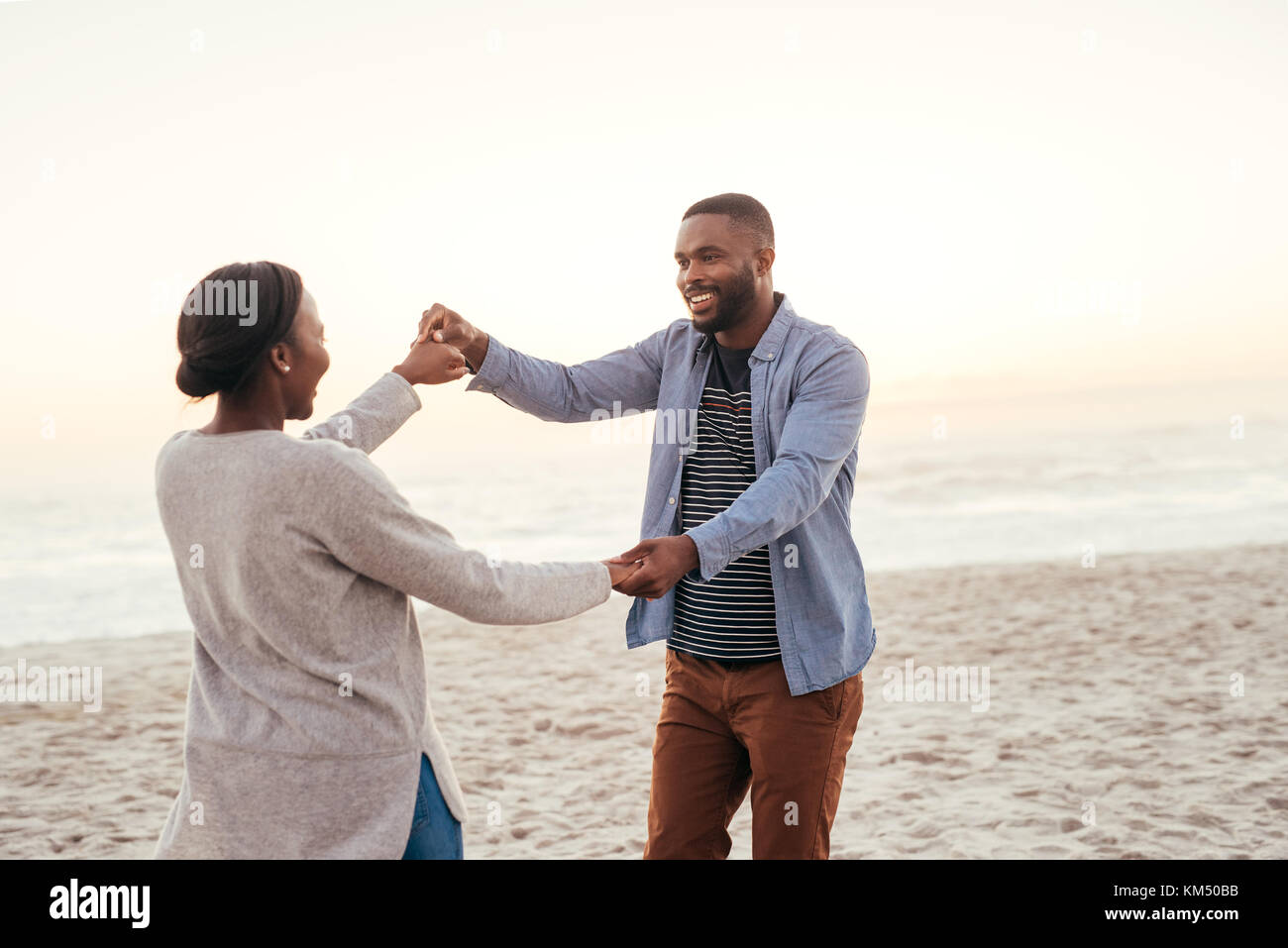 Carefree young African couple dancing together at the beach Stock Photo