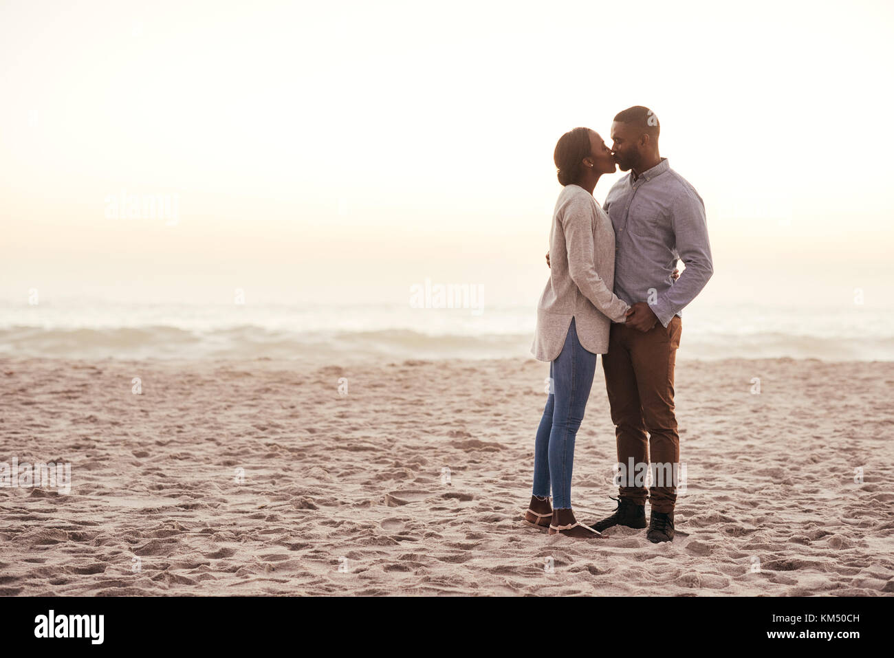 Romantic young African couple kissing on a beach at dusk Stock Photo ...