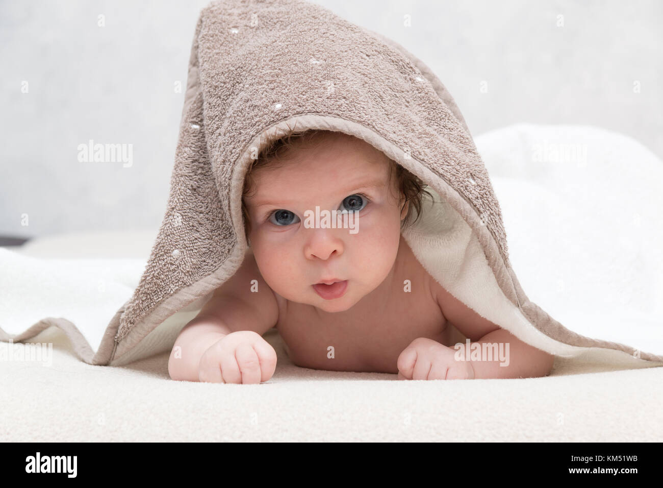 Portrait of sweet naked baby boy or girl with towel on head looking innocently being impressed about something and looking amazed or surprised. Stock Photo
