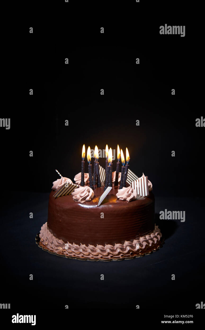 Chockolate birthday cake with candles on black background closeup ...