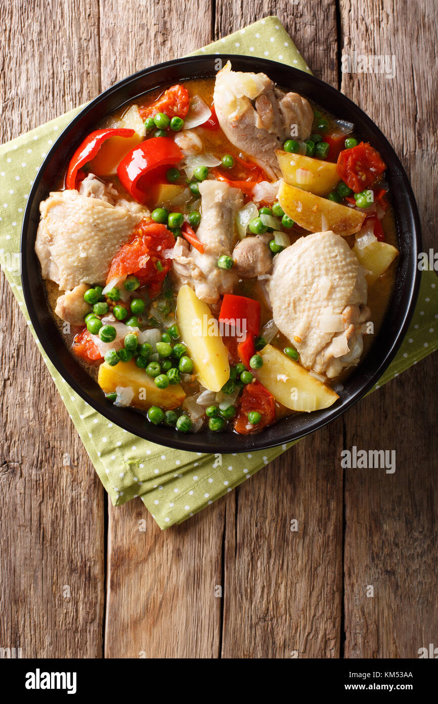 Chicken meat stewed with vegetables and spices close-up in a bowl on the table. Vertical top view from above Stock Photo