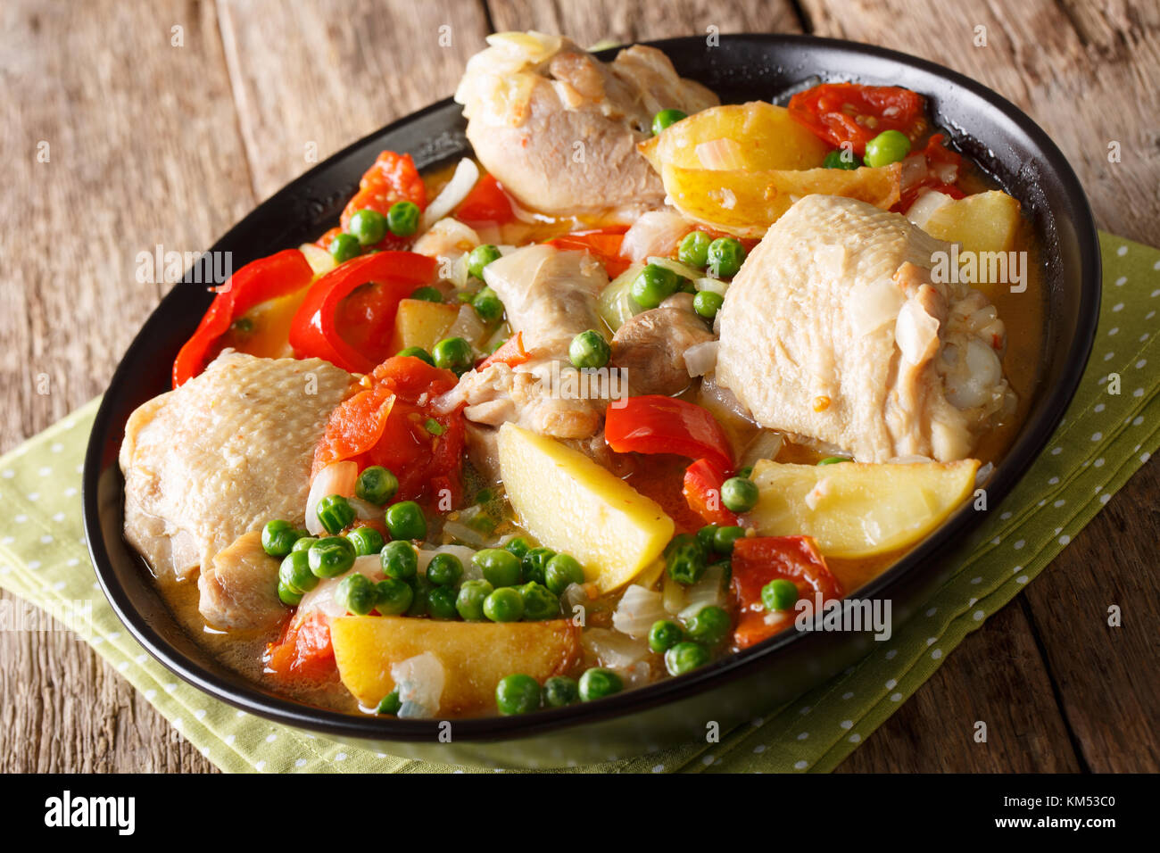 Pieces of chicken stew with potatoes, peppers, tomatoes, peas and onions close-up in a bowl on the table. horizontal Stock Photo