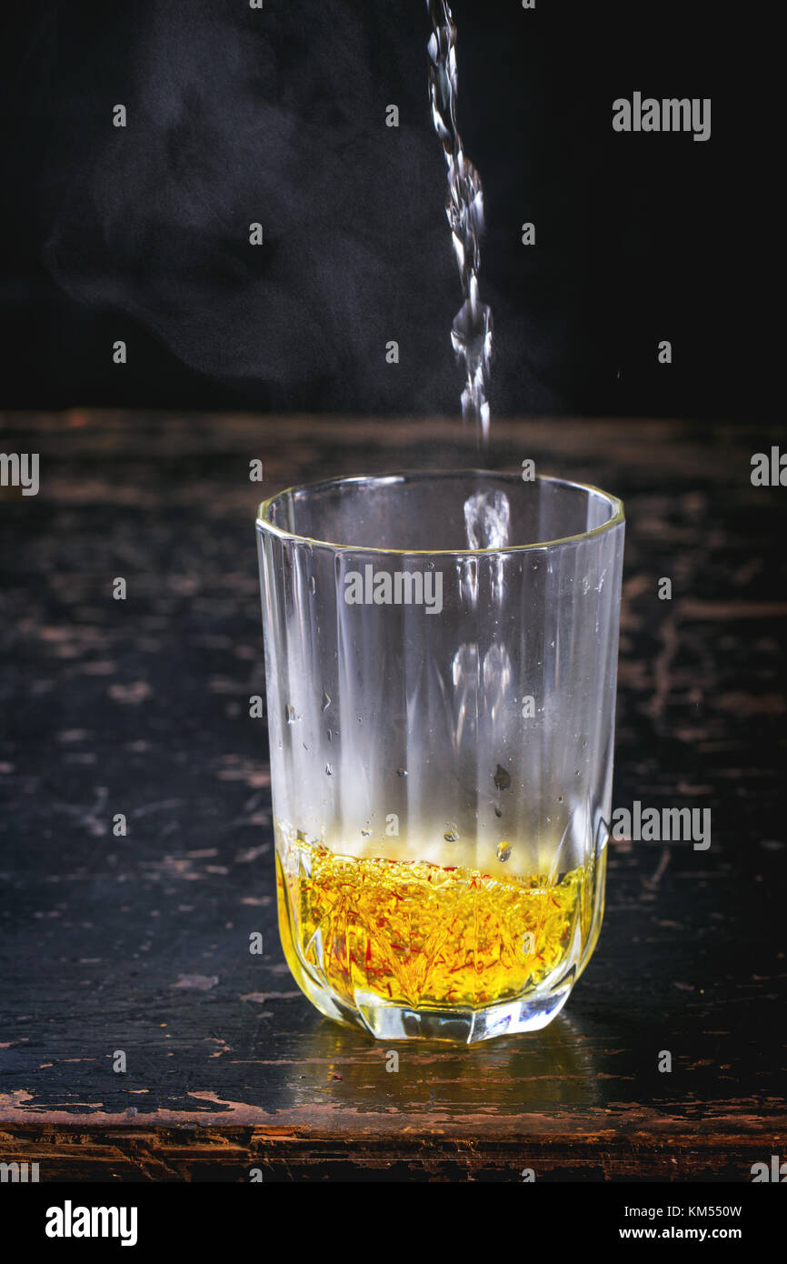 Vintage glass with saffron flowers and pouring hot water Stock Photo